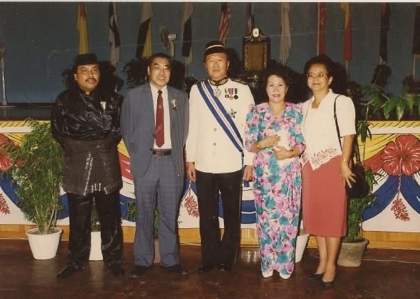 信欣從沙巴教育部退休時獲頒優長服務獎（Anugerah Perkhidmatan Lama）後合影：信欣與月玲，與古達國會議員拿督黃平忠（Wong Phin Chung）伉儷及另一位官員合照